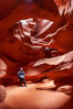 A hiker admiring the striated walls and dramatic light within Antelope Canyon, a deep narrow slot canyon formed by water and wind erosion. Navajo Tribal Lands, Page, Arizona, USA. Image #17995