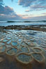 Waves wash over sandstone reef, clouds and sky. La Jolla, California, USA