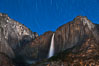 Yosemite Falls and star trails, night sky time exposure of Yosemite Falls waterfall in full spring flow, with star trails arcing through the night sky. Yosemite National Park, California, USA