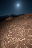 Sky Rock at night, light by moonlight with stars in the clear night sky above.  Sky Rock petroglyphs near Bishop, California. Hidden atop an enormous boulder in the Volcanic Tablelands lies Sky Rock, a set of petroglyphs that face the sky. These superb examples of native American petroglyph artwork are thought to be Paiute in origin, but little is known about them. Image #28504