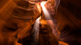 Light Beam in Upper Antelope Slot Canyon.  Thin shafts of light briefly penetrate the convoluted narrows of Upper Antelope Slot Canyon, sending piercing beams through the sandstone maze to the sand floor below. Navajo Tribal Lands, Page, Arizona, USA. Image #28564