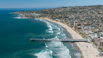 Aerial Photo of Crystal Pier, 872 feet long and built in 1925, extends out into the Pacific Ocean from the town of Pacific Beach. Mission Bay and downtown San Diego are seen in the distance