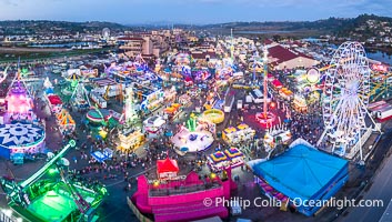 The San Diego County Fair at night, also called the Del Mar Fair, glows with many colorful lights and amusement rides at night in this aerial photo