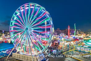 The San Diego County Fair at night, also called the Del Mar Fair, glows with many colorful lights and amusement rides at night in this aerial photo