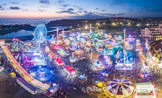 The San Diego County Fair at night, also called the Del Mar Fair, glows with many colorful lights and amusement rides at night in this aerial photo