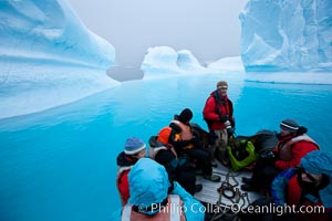 Visitors enjoy an inflatable ride through the strange environs of a bizarrely-shaped iceberg, on a cloudy day, Brown Bluff