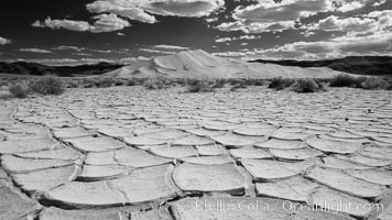 Arid and barren mud flats, dried mud, with the tall Eureka Dunes in the distance.