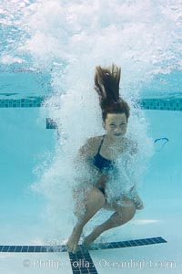 Athletic young girl underwater, performing isometric exercises