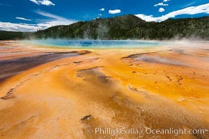Bacteria mats and Grand Prismatic Spring.  The orange color is due to bacteria which thrive only on the cooler fringes of the hot spring, while the hotter center of the spring hosts blue-colored bacteria, Midway Geyser Basin, Yellowstone National Park, Wyoming