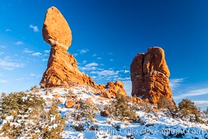 Balanced Rock, a narrow sandstone tower, appears poised to topple.  Sunset, winter, Arches National Park, Utah