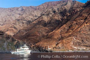 Guadalupe Islands mountainous terrain and sea cliffs tower above the dive boat Horizon while at anchor in Spanish Cove, near the north end of Guadalupe Island (Isla Guadalupe)