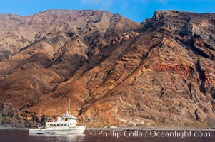 Guadalupe Islands mountainous terrain and sea cliffs tower above the dive boat Horizon while at anchor in Spanish Cove, near the north end of Guadalupe Island (Isla Guadalupe)