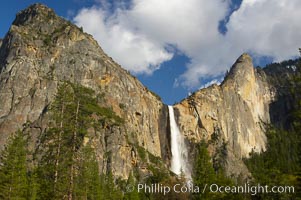 Bridalveil Falls at sunset, with clouds and blue sky in the background.  Bridalveil Falls in Yosemite drops 620 feet (188 m) from a hanging valley to the floor of Yosemite Valley.