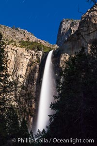 Bridalveil Falls at Night, lit by full moon with a rainbow forming in its spray, dropping 620 into Yosemite Valley, displaying peak water flow in spring months from deep snowpack and warm weather melt, Yosemite National Park, California