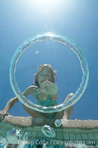 A bubble ring. A young girl reaches out to touch a bubble ring as it ascends through the water toward her