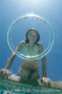 A bubble ring. A young girl watches as a bubble ring ascends through the water toward her