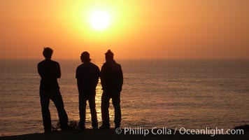 Surf check.  Three guys check the surf from atop a bluff overlooking the waves at the end of the day, at sunset, north of South Carlsbad State Beach