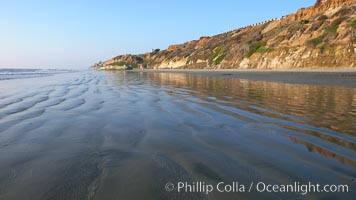 A flat sand beach, sandstone bluffs rise in the background, sunset, Carlsbad, California