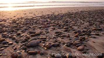 Cobblestones on a flat sand beach.  Cobble stones are polished round and smooth by years of wave energy.  They are alternately exposed and covered by sand depending on the tides, waves and seasons of the year.  Cobblestones are common on the beaches of southern California, contained in the sandstone bluffs along the beach and released onto the beach as the bluffs erode, Carlsbad