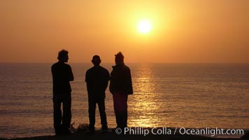 Surf check.  Three guys check the surf from atop a bluff overlooking the waves at the end of the day, at sunset, north of South Carlsbad State Beach