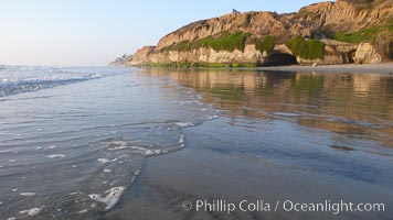 A flat sand beach, sandstone bluffs rise in the background, sunset, Carlsbad, California