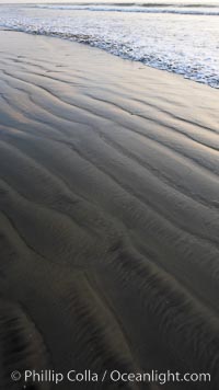 Patterns in the sand on a flat sandy beach at the water's edge, Carlsbad, California