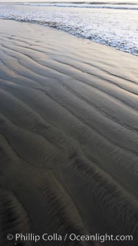 Patterns in the sand on a flat sandy beach at the water's edge, Carlsbad, California