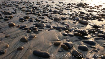 Cobblestones on a flat sand beach.  Cobble stones are polished round and smooth by years of wave energy.  They are alternately exposed and covered by sand depending on the tides, waves and seasons of the year.  Cobblestones are common on the beaches of southern California, contained in the sandstone bluffs along the beach and released onto the beach as the bluffs erode.