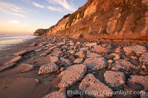 Remains of the old historic "Coast Highway 101", undermined as the bluff upon which it was built eroded away, now broken into pieces of concrete and asphalt blocks and fallen down the sea cliffs, lying on the beach, Carlsbad, California