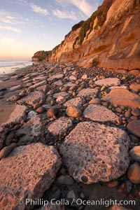 Remains of the old historic "Coast Highway 101", undermined as the bluff upon which it was built eroded away, now broken into pieces of concrete and asphalt blocks and fallen down the sea cliffs, lying on the beach, Carlsbad, California