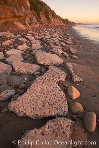 Remains of the old historic "Coast Highway 101", undermined as the bluff upon which it was built eroded away, now broken into pieces of concrete and asphalt blocks and fallen down the sea cliffs, lying on the beach, Carlsbad, California