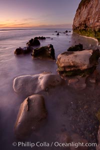 Sunset, sea cliffs, rocks and swirling water blurred in a long time exposure.