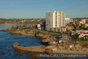 The Children's Pool in La Jolla, also known as Casa Cove, is a small pocket cove protected by a curving seawall, with the rocky coastline and cottages and homes of La Jolla seen behind it