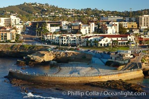 The Children's Pool in La Jolla, also known as Casa Cove, is a small pocket cove protected by a curving seawall, with the rocky coastline and cottages and homes of La Jolla seen behind it