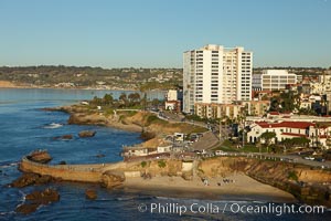 The Children's Pool in La Jolla, also known as Casa Cove, is a small pocket cove protected by a curving seawall, with the rocky coastline and cottages and homes of La Jolla seen behind it