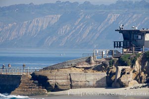 Children's Pool lifeguard tower and sea wall with tourists, Torrey Pines golf course and Black's Beach in the distance, La Jolla, California