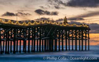 The Crystal Pier, Holiday Lights and Pacific Ocean at sunset, waves blur as they crash upon the sand. Crystal Pier, 872 feet long and built in 1925, extends out into the Pacific Ocean from the town of Pacific Beach