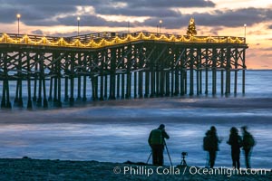 The Crystal Pier, Holiday Lights and Pacific Ocean at sunset, waves blur as they crash upon the sand. Crystal Pier, 872 feet long and built in 1925, extends out into the Pacific Ocean from the town of Pacific Beach