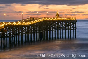 The Crystal Pier, Holiday Lights and Pacific Ocean at sunset, waves blur as they crash upon the sand. Crystal Pier, 872 feet long and built in 1925, extends out into the Pacific Ocean from the town of Pacific Beach
