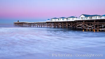 The Crystal Pier and Pacific Ocean at sunrise, dawn, waves blur as they crash upon the sand.  Crystal Pier, 872 feet long and built in 1925, extends out into the Pacific Ocean from the town of Pacific Beach