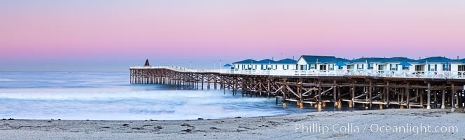 The Crystal Pier and Pacific Ocean at sunrise, dawn, waves blur as they crash upon the sand.  Crystal Pier, 872 feet long and built in 1925, extends out into the Pacific Ocean from the town of Pacific Beach