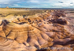 Dawn breaks over the Bentonite Hills in the Utah Badlands.  Striations in soil reveal layers of the Morrison Formation, formed in swamps and lakes in the Jurassic era. Aerial panoramic photograph