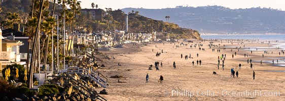 Del Mar Beach on the extreme low King Tide, people and dogs walking on the beach, late afternoon