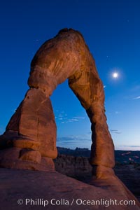 Delicate Arch and the Moon at Sunset.  The moon and clouds, with stars showing faintly in the sky, as sunset fades into night, Arches National Park, Utah