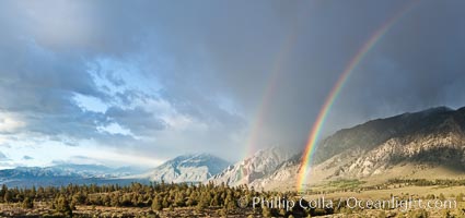 A double rainbow forms in storm clouds over Swall Meadows and Round Valley, at sunrise in the Eastern Sierra Nevada, California.