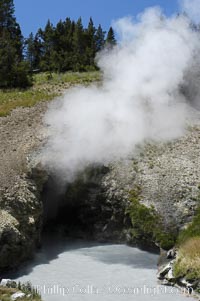 Dragons Mouth hot spring is a hot spring fronted by a pool churned by steam, carbon dioxide and hydrogen sulfide vapors roiling up through the pool formed in the springs cavernous mouth.  Mud Volcano area, Yellowstone National Park, Wyoming