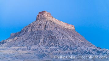 Factory Butte at sunrise. An exceptional example of solitary butte surrounded by dramatically eroded badlands, Factory Butte stands alone on the San Rafael Swell, Hanksville, Utah