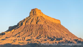 Factory Butte at sunrise. An exceptional example of solitary butte surrounded by dramatically eroded badlands, Factory Butte stands alone on the San Rafael Swell, Hanksville, Utah