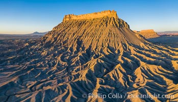 Factory Butte at sunrise, aerial photo, Utah. An exceptional example of solitary butte surrounded by dramatically eroded badlands, Factory Butte stands alone on the San Rafael Swell, Hanksville