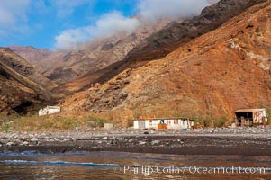 Guadalupe Islands steep cliffs tower above a small fishing shack, lighthouse, old chapel and prison near the north end of Guadalupe Island (Isla Guadalupe)